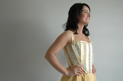 The corset is made of strips of yellow and brocade fabric.